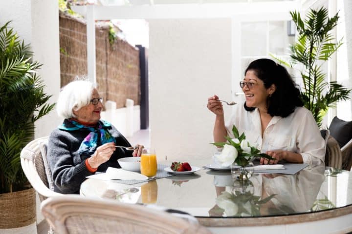 Older lady with carer eating at a table